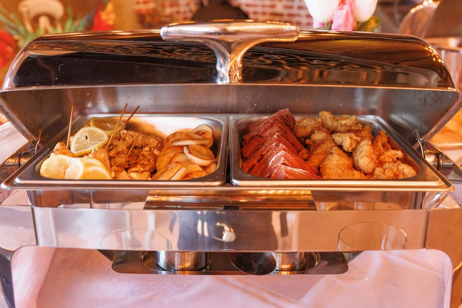 Warm buffet station with chicken skewers, rolls, and fried bites